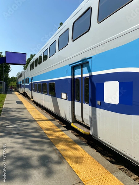 Fototapeta City train at the station ready for departure. Close up of wagons, windows and doors of a suburban train at the boarding platform. Display panel for travel times.