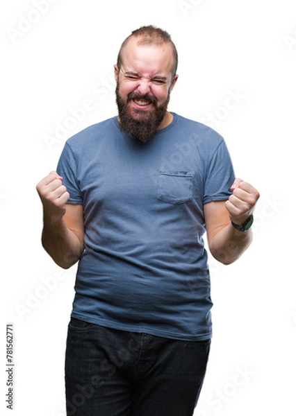 Fototapeta Young caucasian hipster man over isolated background very happy and excited doing winner gesture with arms raised, smiling and screaming for success. Celebration concept.