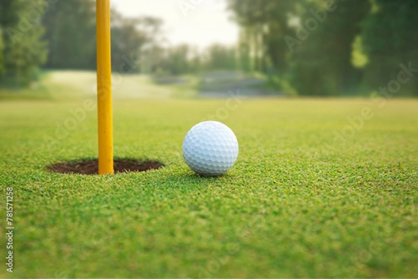 Obraz Close up of golf ball on a green near hole with pin