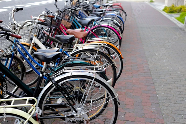 Fototapeta A group of bicycles lined up in a row on the sidewalk.