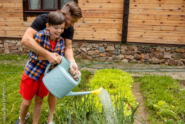 Fototapeta 
happy dad and son are watering plants in the garden. country concept. man and boy taking care of the garden