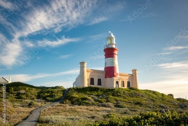 Fototapeta Image of a white and red lighthouse on the top of the mount under the blue sky.