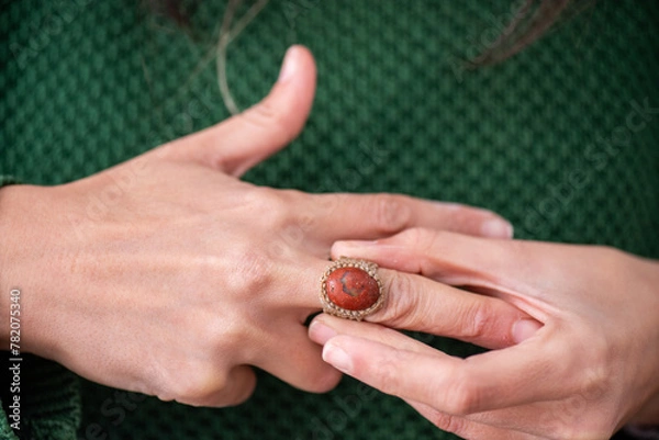 Obraz detail of a woman's hands putting on a ring with a stone and woven fabric