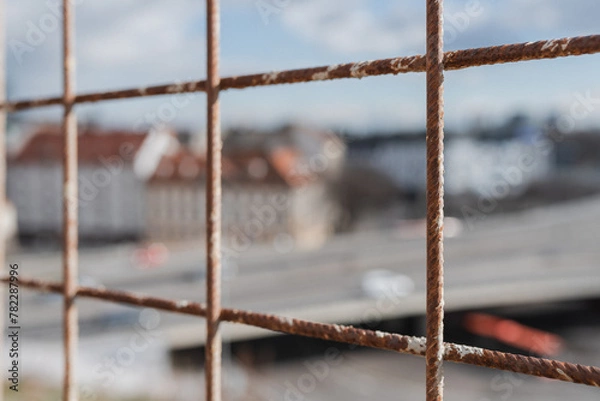 Fototapeta Rusty fence in view of town