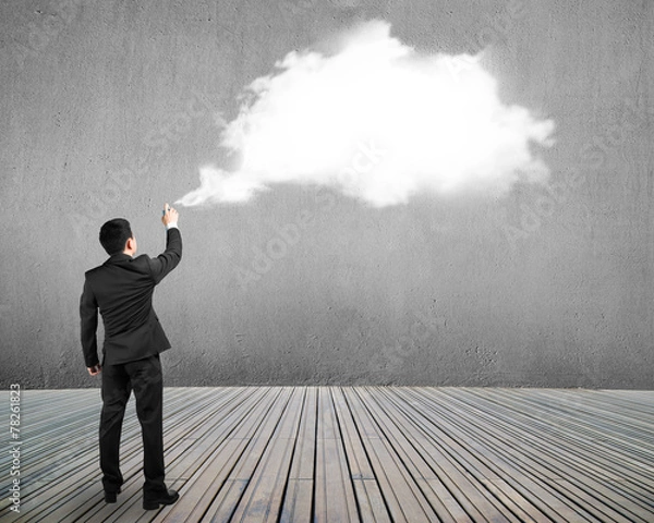 Fototapeta Businessman spraying white cloud paint on gray concrete wall