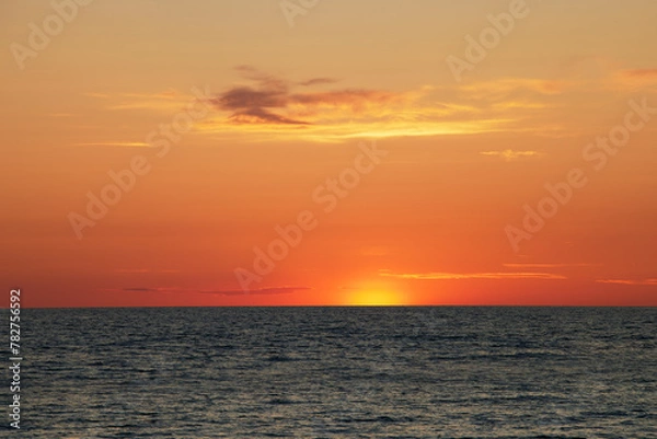 Fototapeta A beautiful view of a sunset where the sun har just set below the horizon creating lovely colours in the sky and the clouds.