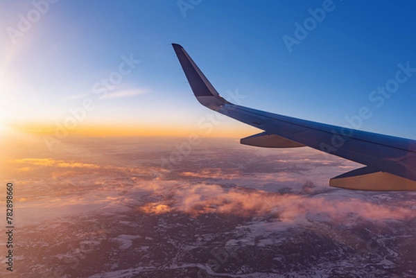 Fototapeta Airplane flying low over snowy mountains and preparing for landing to the airport, view from plane window of wing turbine and skyline