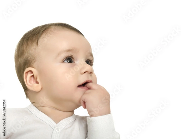 Obraz Cute baby boy with hand in the month looking up curiously.