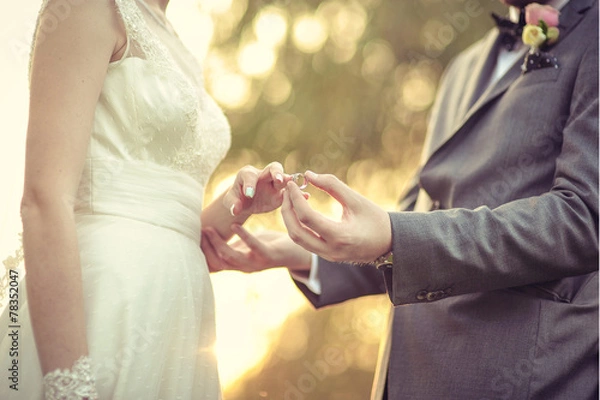 Obraz Groom putting wedding ring on bride's finger