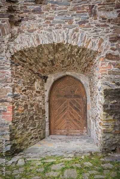 Obraz Old wooden door in an old stone wall with arches in a medieval castle