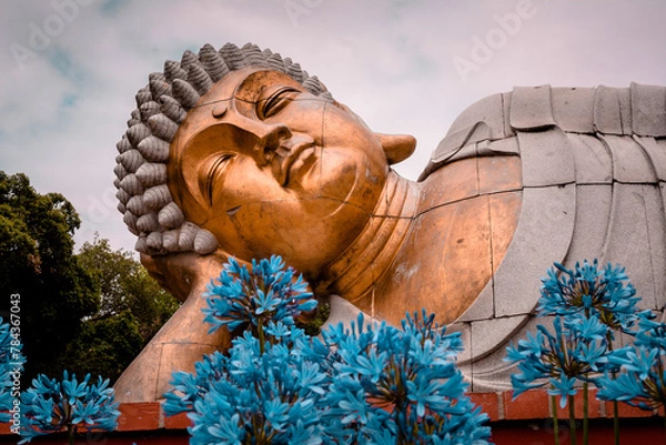 Fototapeta Buddha lying down with hand on head and flowers