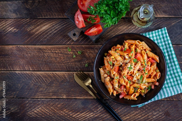 Fototapeta Classic italian pasta penne arrabbiata with vegetables on wooden table. Penne pasta with sauce arrabbiata. Top view, overhead