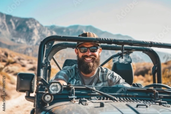 Fototapeta Smiling bearded man driving his off-road car in the mountains