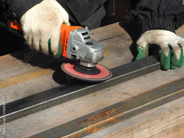Obraz A worker processes metal with an angle grinder on a construction site.
The concept of locksmith work, processing of metal products.
