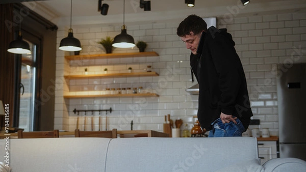 Fototapeta Man in a hurry to go to work, wearing jeans and talking on the phone, hurriedly gets ready for work.
