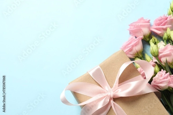 Fototapeta Happy Mother's Day. Beautiful flowers and gift box on light blue background, flat lay. Space for text