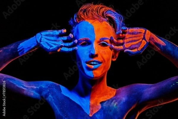 Fototapeta Man covered with fluorescent paint playing in the dark