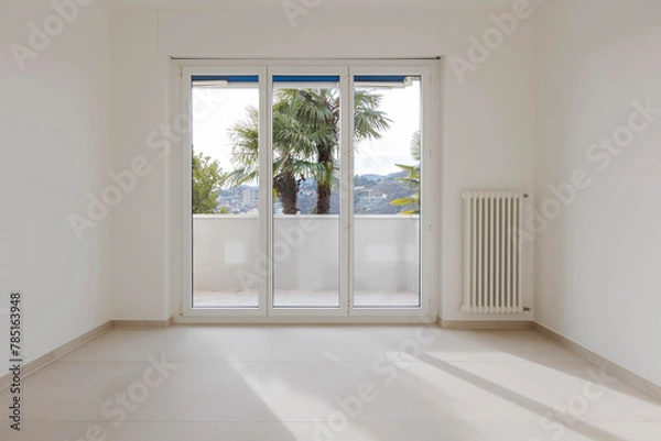 Obraz Empty space sconces an open sliding door in the background. On the ceiling there is a lighted LED and to the right a large window leading onto the balcony. It is a vuotom and modern, new flat. 