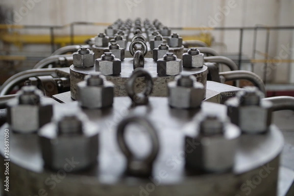 Fototapeta Panoramic view of flange bolts arranged in a circle against an industrial background. Large flange bolts.