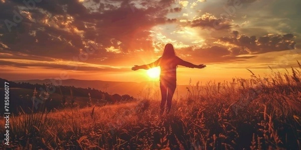 Fototapeta Serene sunset silhouette of one person with outstretched arms in golden field, vibrant summer evening colors, freedom concept, wellbeing theme.