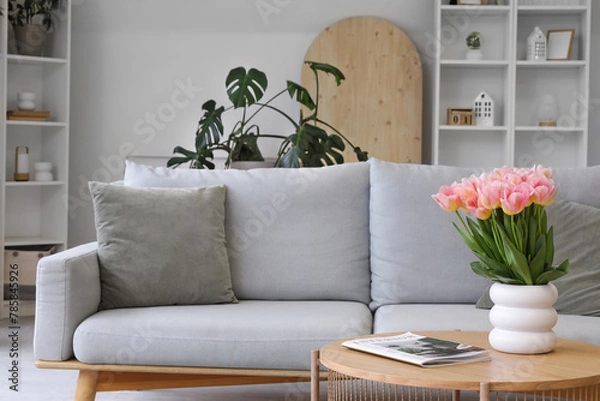 Fototapeta Stylish interior of living room with comfortable sofa and tulips