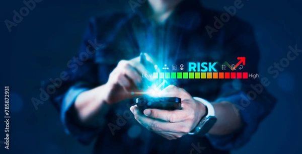 Fototapeta A person is holding a cell phone with a blue screen that says "risk" on it