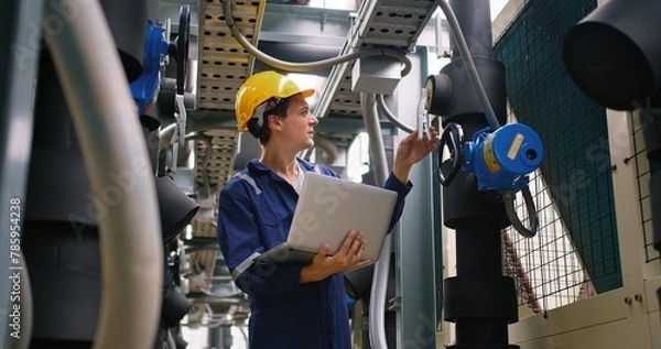 Obraz engineer using laptop checking industry cooling air conditioner water cooling tower air chiller of large industrial building to control air system at construction site