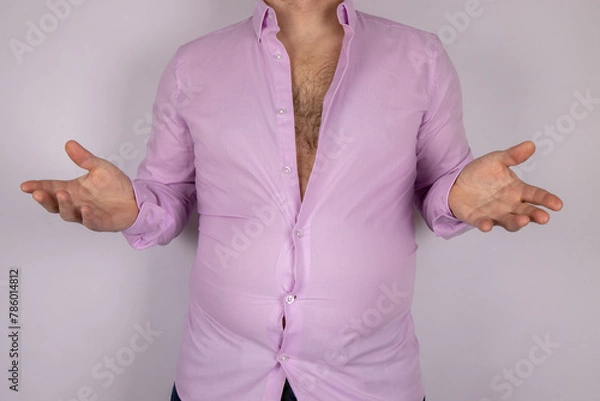 Fototapeta A middle aged slightly over weight man in a pink shirt that is now too small due to the man putting on weight and needed to go on a diet, time for a diet concept.