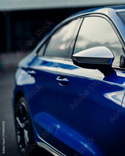 Fototapeta Side shot of a shiny blue sport car mirror and windows with blur background, vertical shot