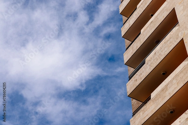 Fototapeta Geometric perfection. A part of modern apartment building against partly cloudy sky.