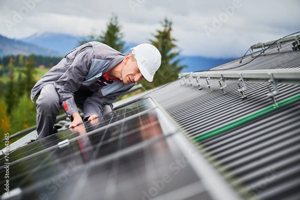 Fototapeta Competent technician adjusting position of solar panel. Solar photovoltaic cell installation on a top of house. Green energy sourses concept.