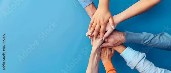 Fototapeta Capturing the essence of team spirit, a multi-ethnic group of individuals join hands in unity against a blue background