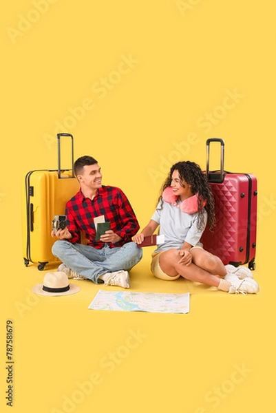 Fototapeta Couple of tourists with suitcases, passports and map sitting on yellow background