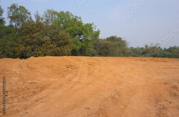 Obraz Red mud land with greenery and blue sky in the background