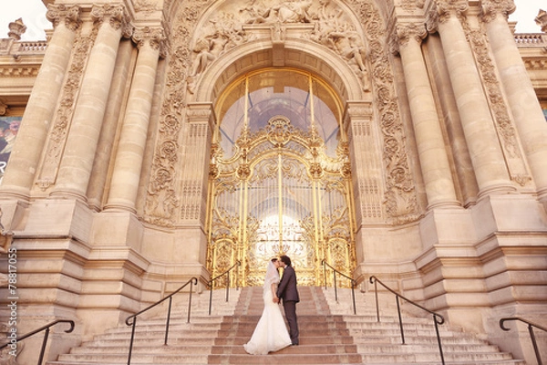 Fototapeta Bride and groom in front of a big building