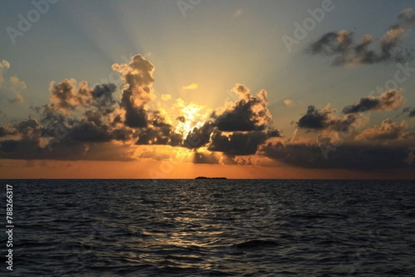 Fototapeta Dramatic cloudy skies on sunset over ocean waters