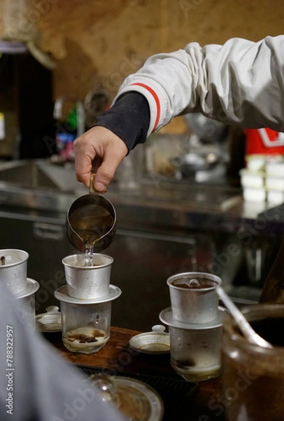 Obraz Local barista pouring water in the phin to make Vietnamese dripping coffee
