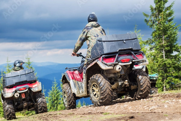 Fototapeta Tourist on ATV driving through the mountains in stormy weather