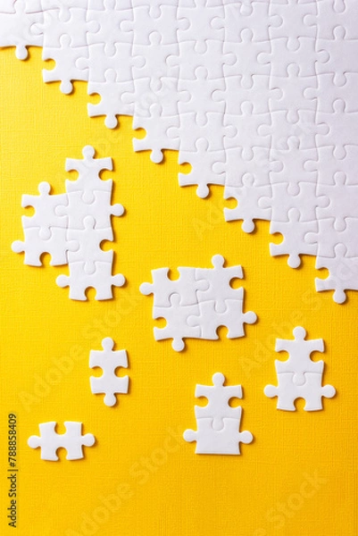 Fototapeta Jigsaw puzzle for business concept on yellow background. Idea of partnership and teamwork. Vertical poster
