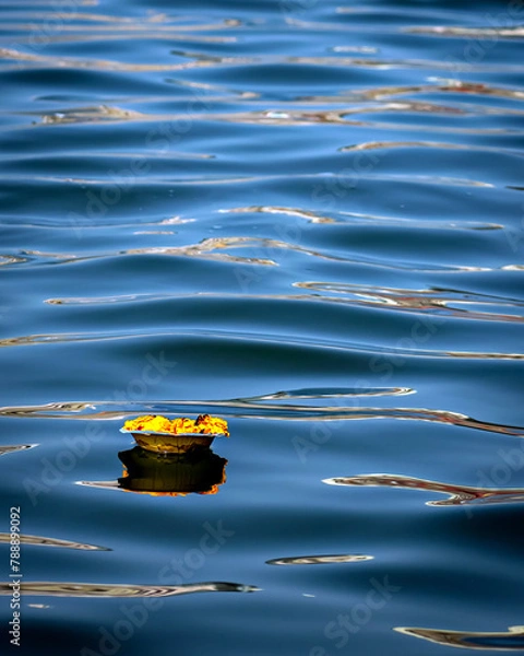 Obraz Isolated image of a floating lamp with flowers and candle offered to holy river Ganges at Varanasi Ghats.