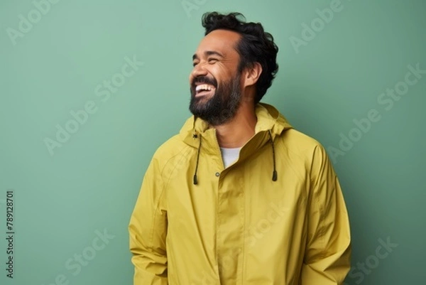 Fototapeta Portrait of a happy man in his 40s sporting a waterproof rain jacket isolated in solid pastel color wall