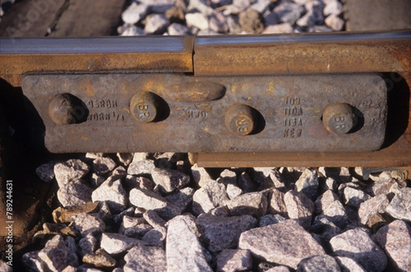Fototapeta horizontal image of railway track section with bolts and stones under lying lines at woodbridge rail station suffolk uk in 2003. closeup view.