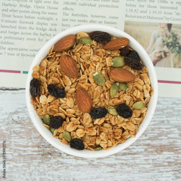 Fototapeta Top view of Homemade granola with mix nuts in a white bowl. Healthy snack and breakfast.