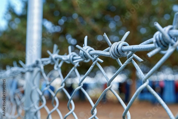 Fototapeta A chain link fence with barbed wire on top