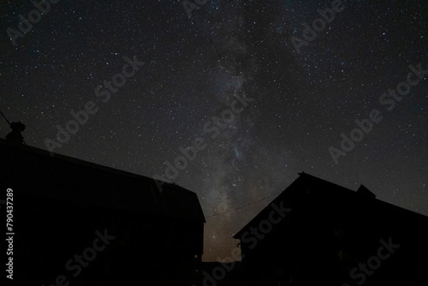 Fototapeta A starry night sky with the Milky Way over some farm buildings