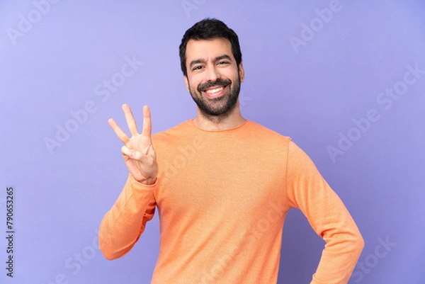 Fototapeta Caucasian handsome man over isolated purple background happy and counting three with fingers