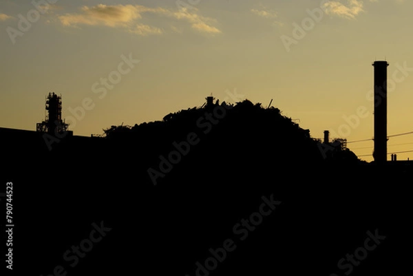 Fototapeta 工業地帯の夕暮れとシルエットになったスクラップの山
