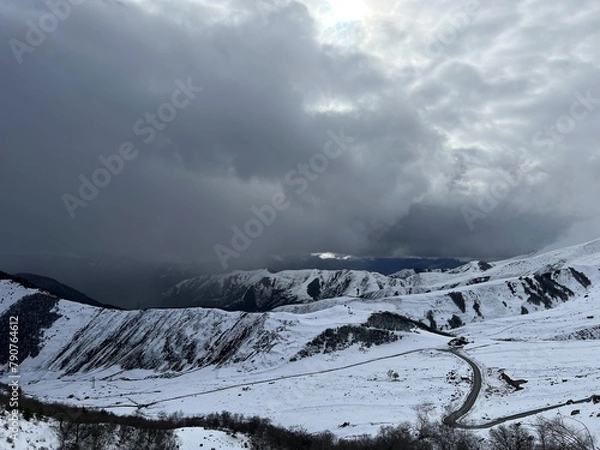 Fototapeta Tseylomsky pass in Ingushetia. A trip uphill to the Tsei Loam pass on a cloudy spring day. Panorama of the high cliffs of the Dzheyrakh gorge. North Caucasus, Russia