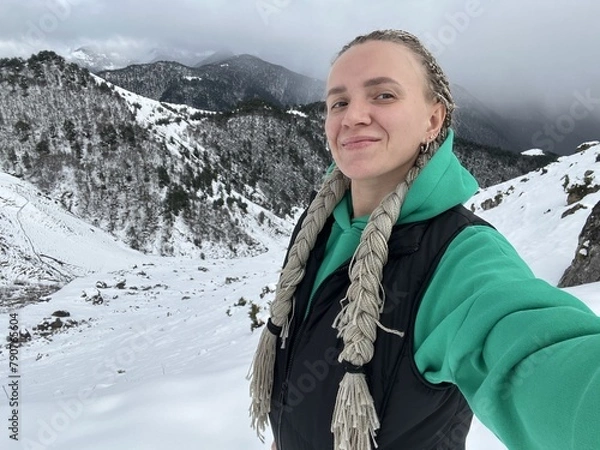Fototapeta A woman on the background of the Ceylomsky pass in Ingushetia. A trip uphill to the Tsei Lum pass on a cloudy spring day. Panorama of the high cliffs of the Dzheyrakh gorge