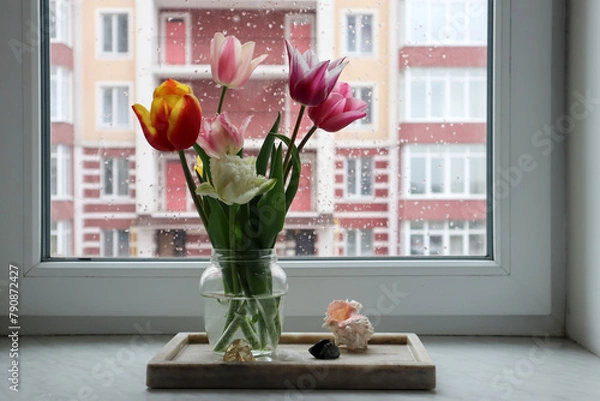 Fototapeta Colorful tulips in vase on the windowsill at rainy weather. Home decor with flowers.